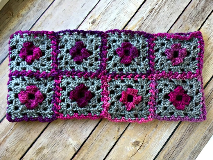 granny crochet cowl pattern made from floral granny squares lying flat on a wooden background