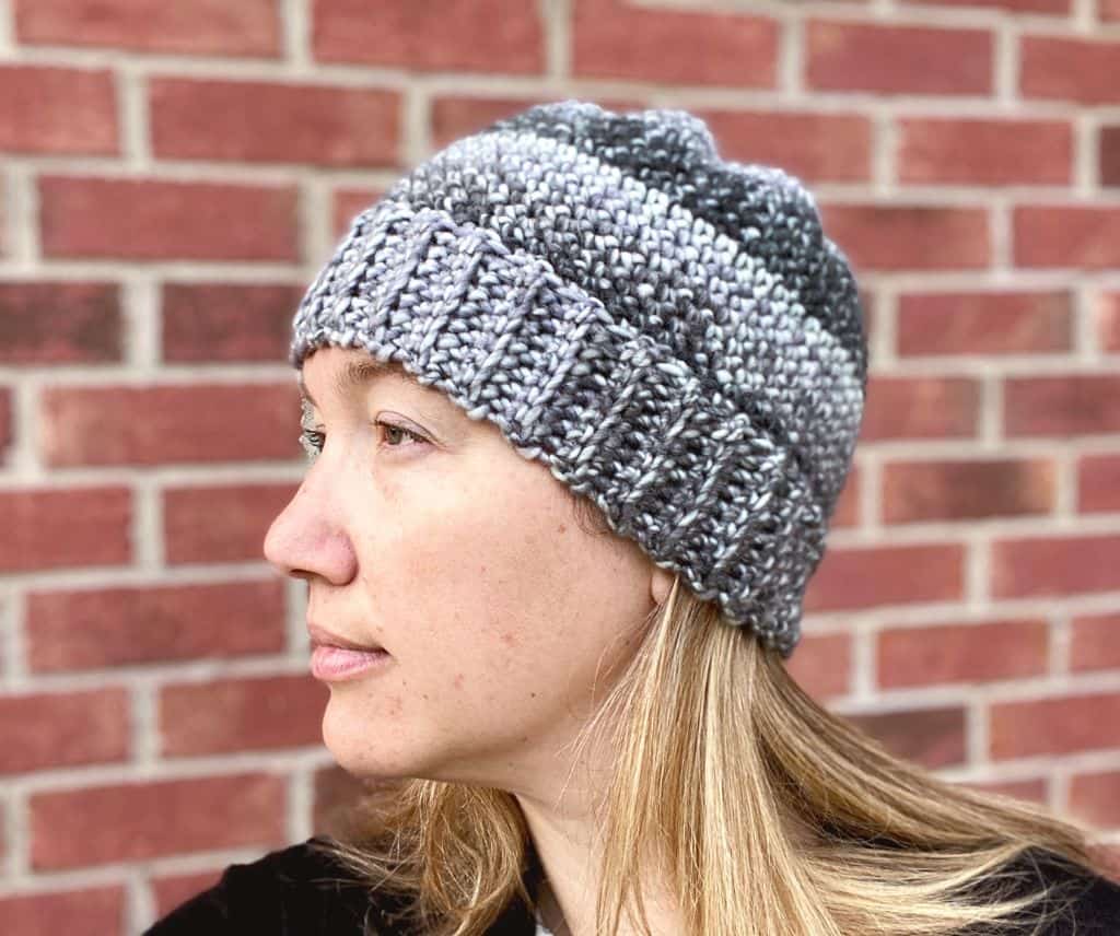 designer wearing the basic crochet beanie in front of brick wall