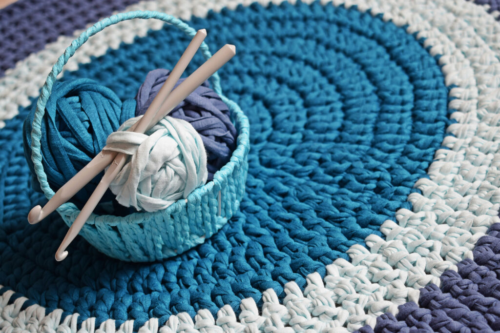 hooks and t-shirt yarn in a basket on a crochet rug