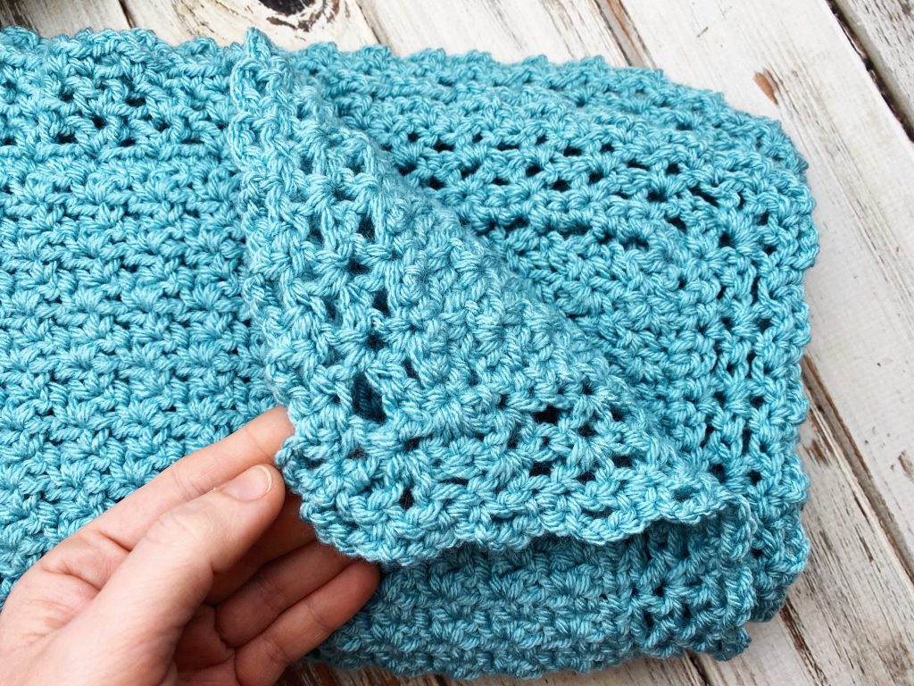 hand holding back corner of classic chunky crochet baby blanket