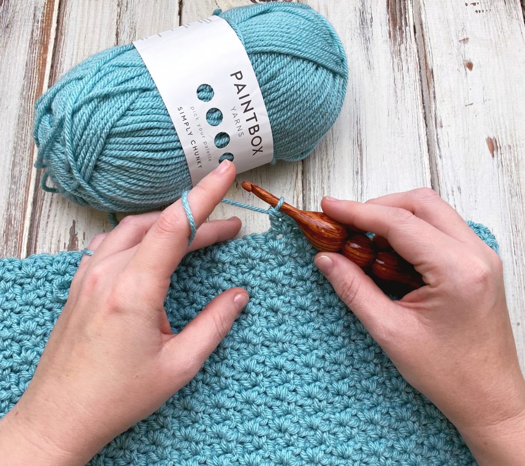 A hand holding a doing a crochet stitches patterns