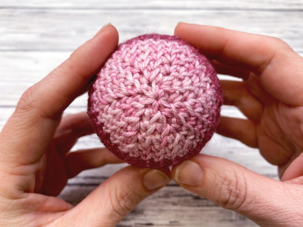 hands holding the crochet Easter egg showing the bottom of the egg
