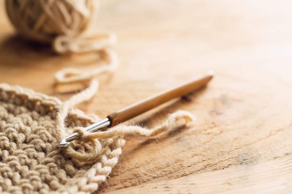 crochet hook on wooden table with work in progress