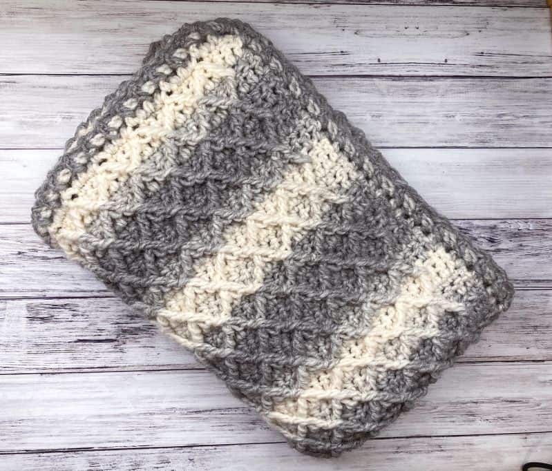 diamond stitch crochet blanket folded and sitting on wooden background