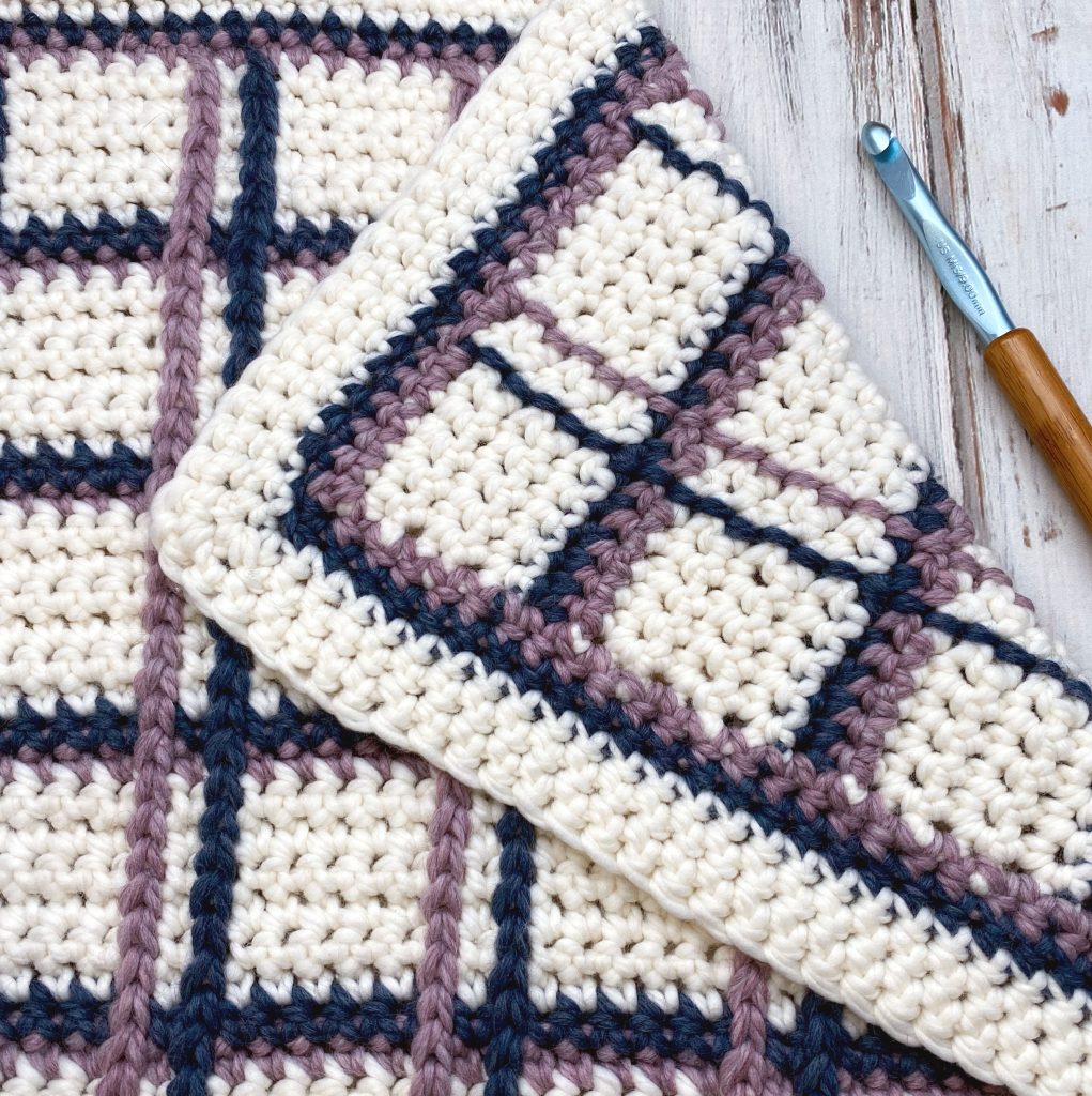 Tartan Plaid Baby Blanket on wooden background with crochet hook