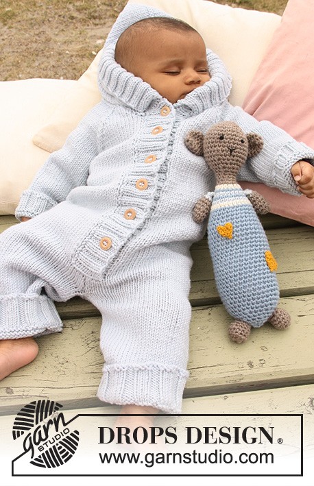 sleeping baby in light blue romper with crochet stuffed animal