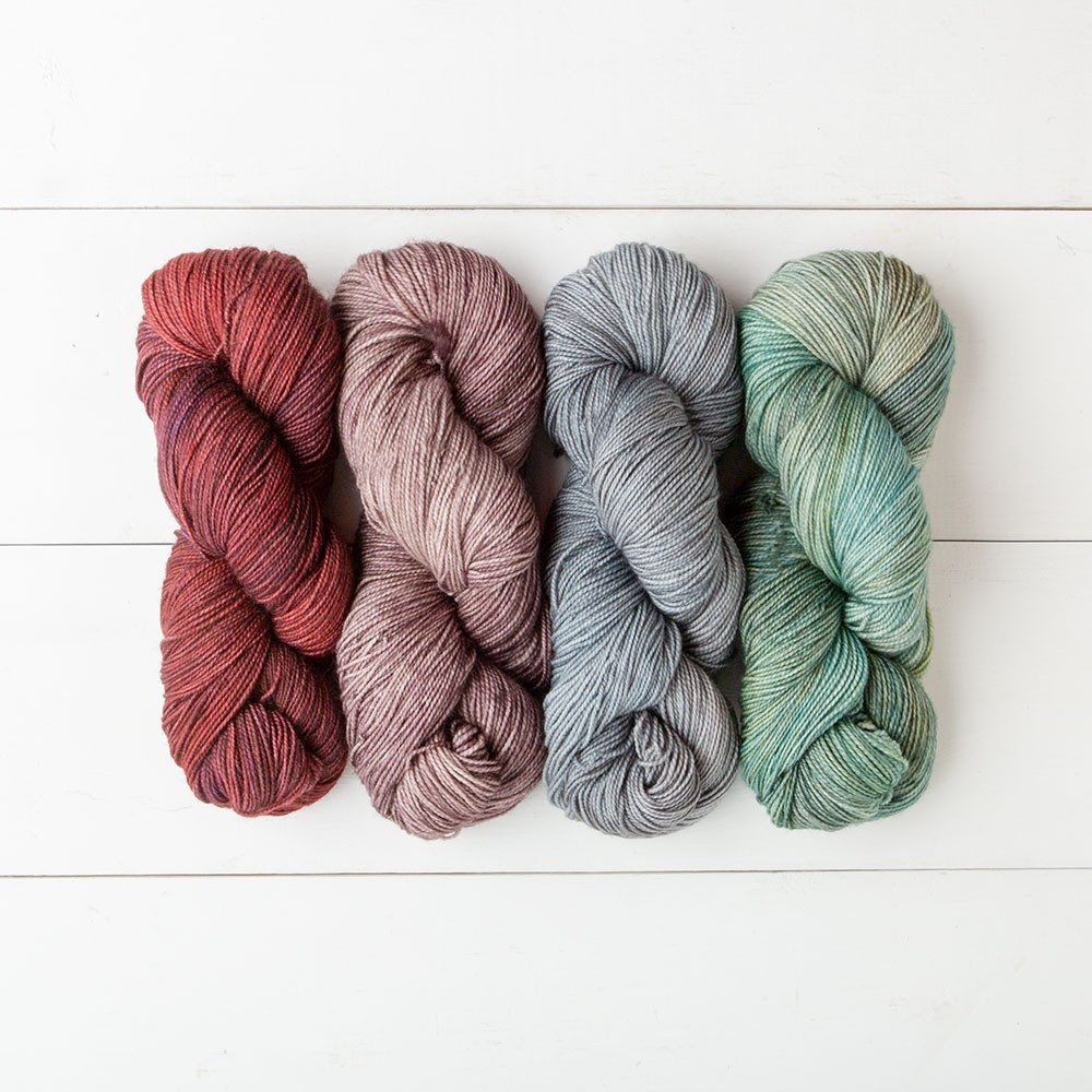 four hanks of knit picks hawthorne tonal yarn on white wooden background