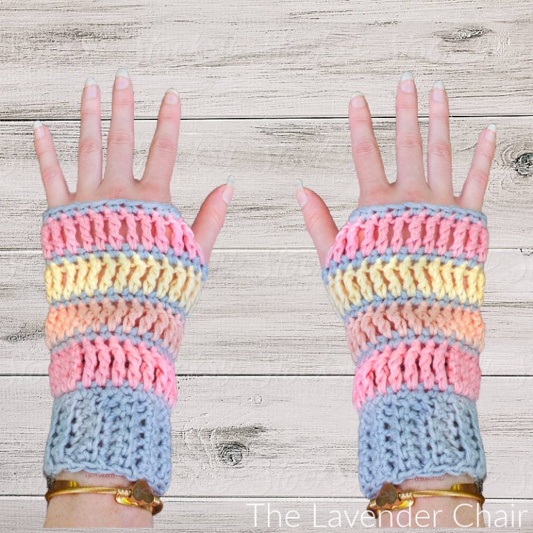 hands modeling a pair of crochet fingerless gloves over wooden background