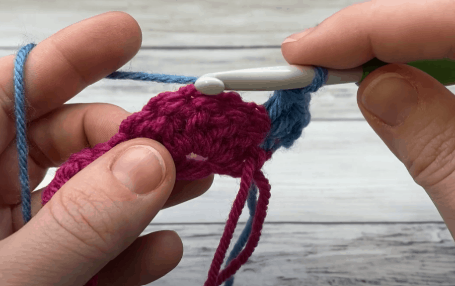 a hand doing Single crochet in center double crochet stitch of next shell